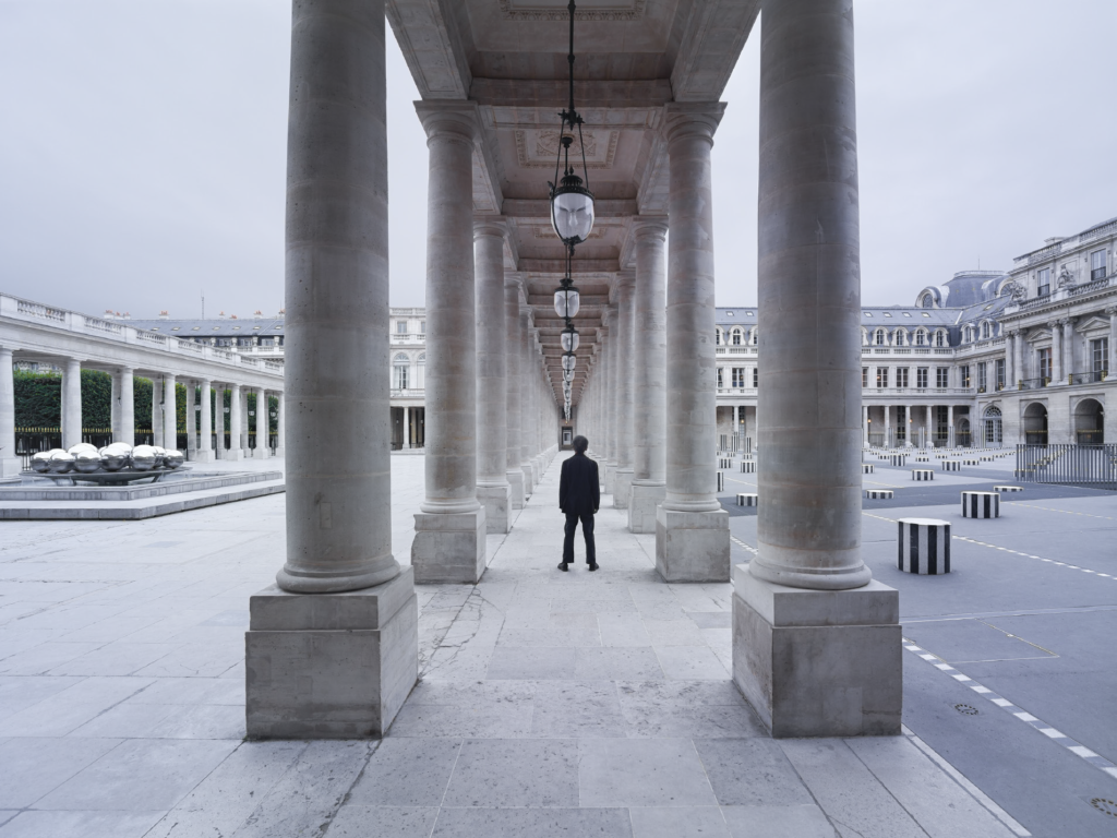 Photograph of a person with his back to a colonnade in Paris