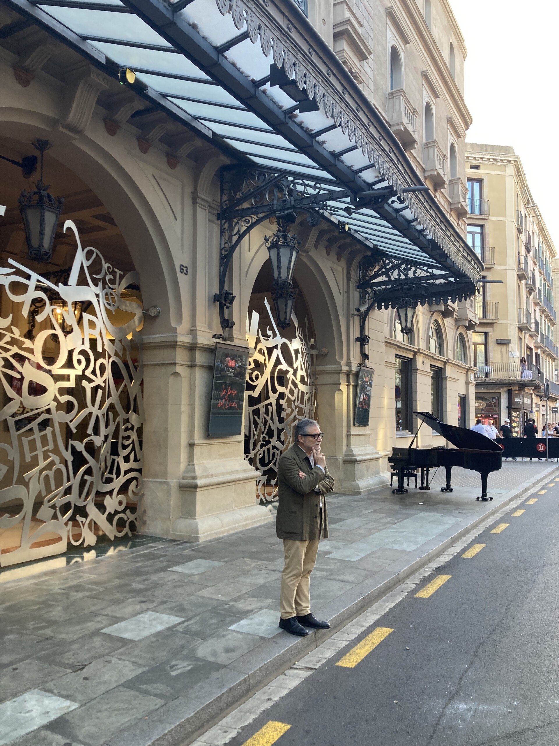Photograph of a man in front of the doors of the Liceo and next to a grand piano