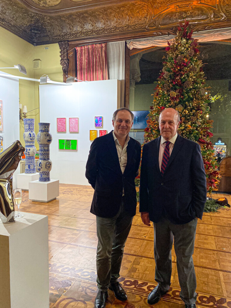 Imatge de dos homes amb americana posant davant d'una exposició d'art