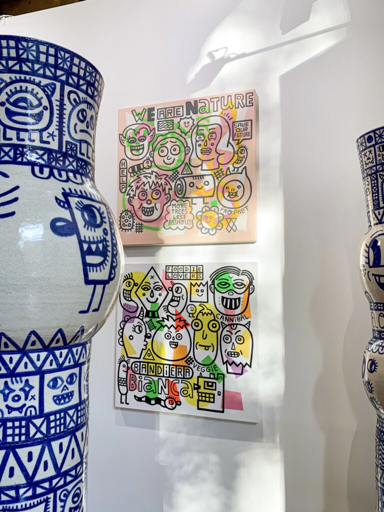 Imagen de dos cuadros coloridos con siluetas de caras trazadas en negro y un jarrón de cerámica con caras trazadas en azul