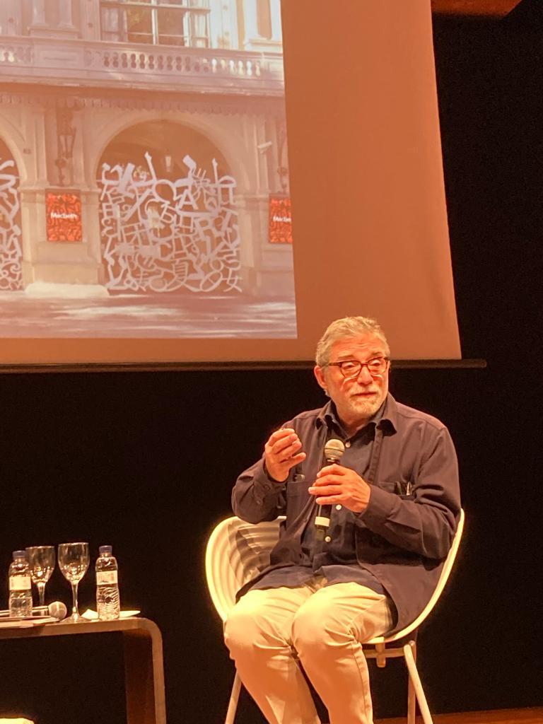 Photograph of Jaume Plensa seated on a chair with a microphone in hand 