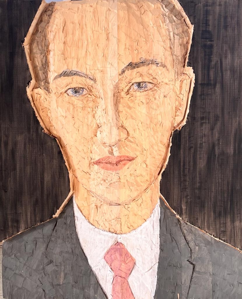 Wooden sculpture of a man with black jacket, white shirt and pink tie