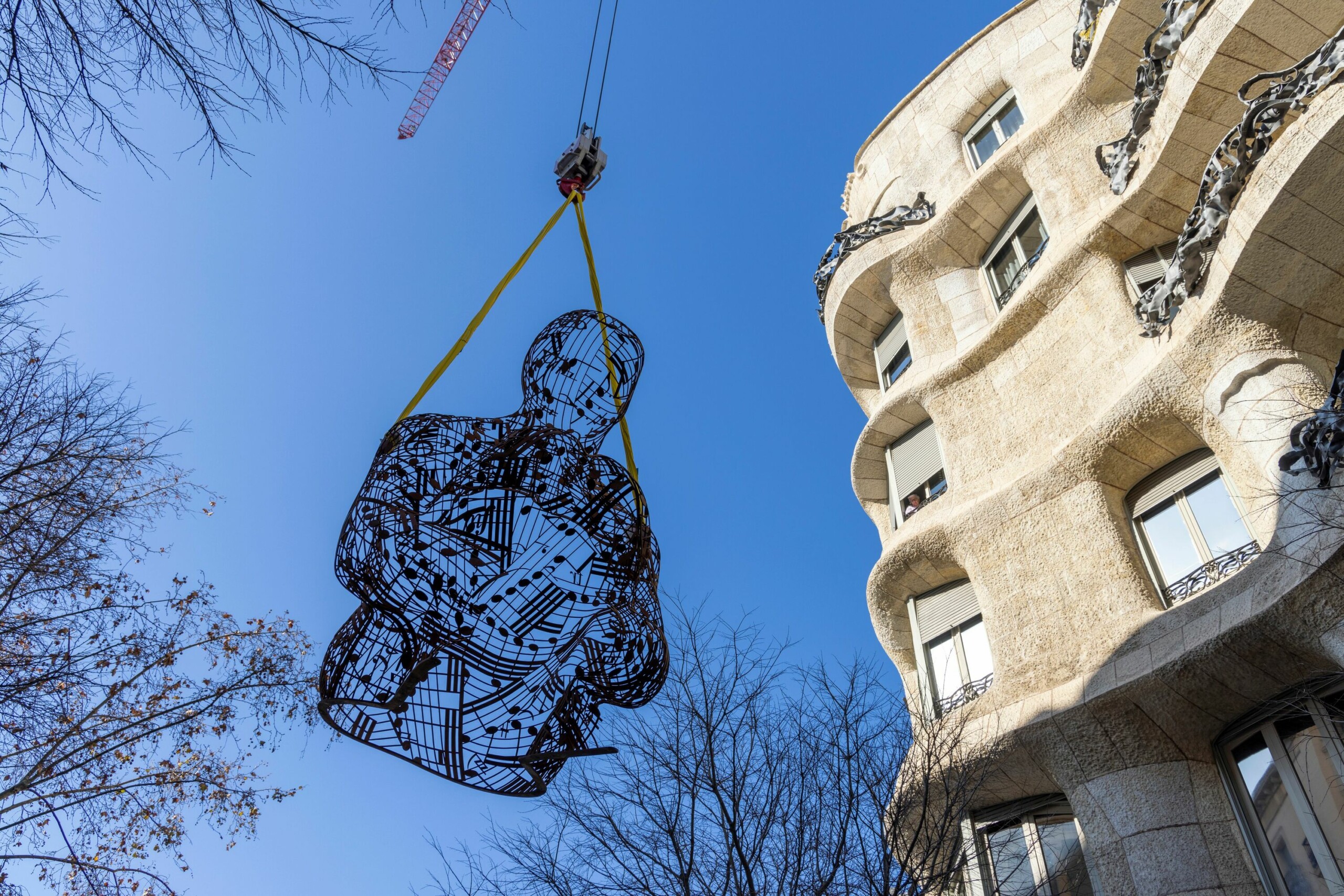 Imatge d'una escultura de metall sent pujada per una grua cap a La Pedrera