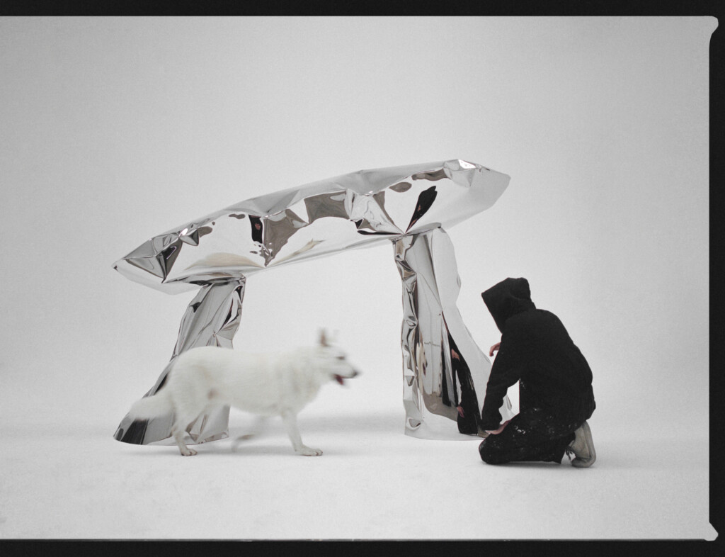Person and white dog in front of a steel sculpture